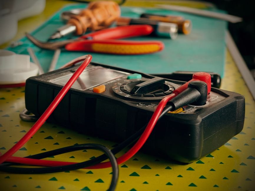 A multimeter and electrical testing tools on a workbench, the type of equipment used by a certified PAT tester in Glasgow