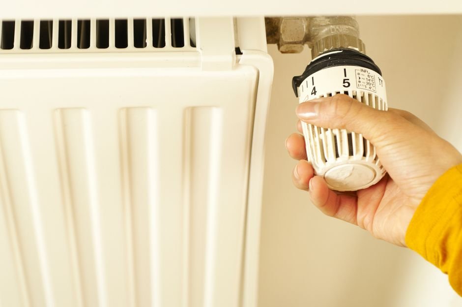 Homeowner adjusting a radiator thermostatic valve — part of checking your central heating system before an annual boiler service in Glasgow