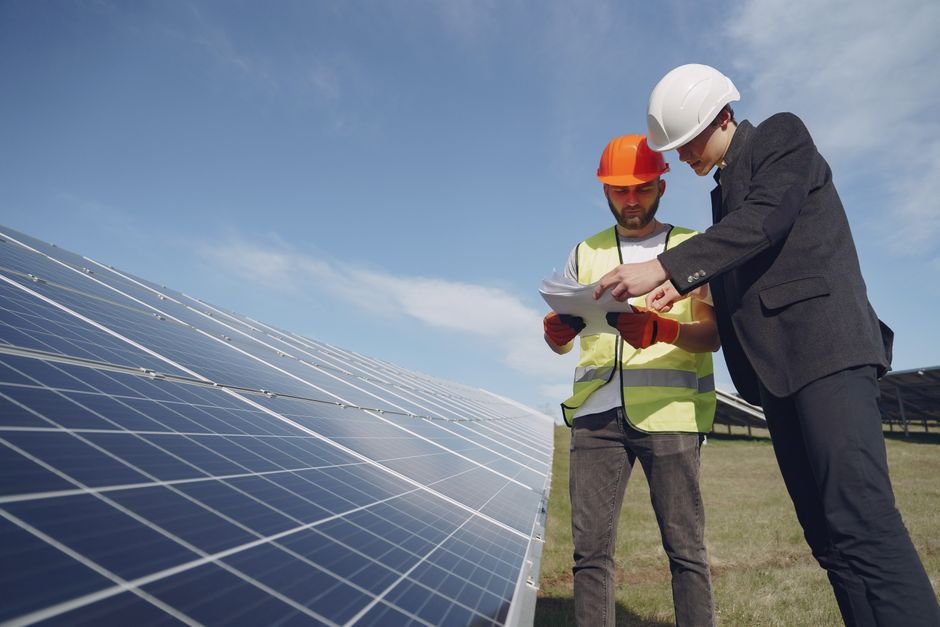 Electrician and inspector in hard hats checking documentation on site, representing the credential checks worth doing before hiring in Ayrshire