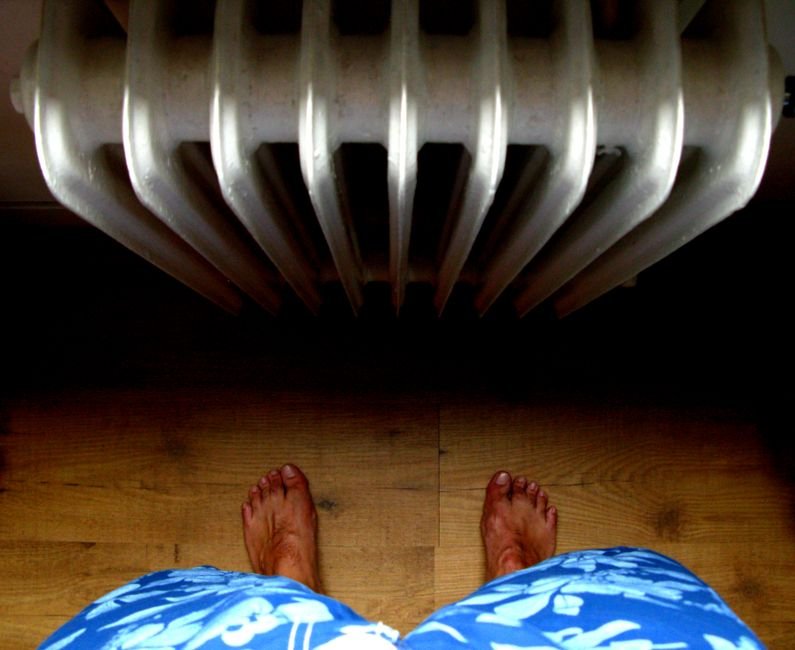 Bare feet on a wooden floor beside a warm radiator, the payoff of a working boiler in a Hamilton home