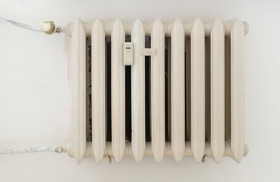 A modern white radiator in a bright, renovated room, part of the central heating system a new boiler needs to run properly