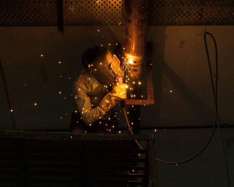 Tradesperson welding steel pipes indoors, a nod to Coatbridge's Iron Burgh heritage and the plumbers and heating engineers working the Monklands today
