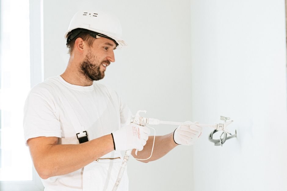 Electrician wearing safety gear installing new wiring in a Clydebank property