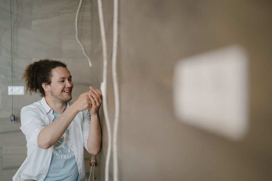 Domestic electricity meter and fuse box mounted on a wall, the kind of consumer unit an electrician checks during rewiring or an EICR