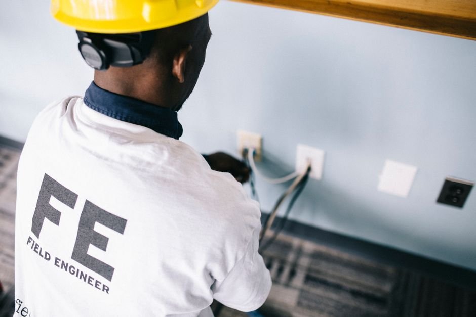 Electrician testing voltage at wall sockets indoors, the kind of check carried out during an EICR electrical safety inspection