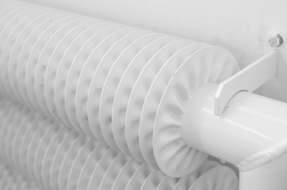 White finned central heating radiator mounted on a wall, typical of the central heating systems in Giffnock's interwar bungalows and semis
