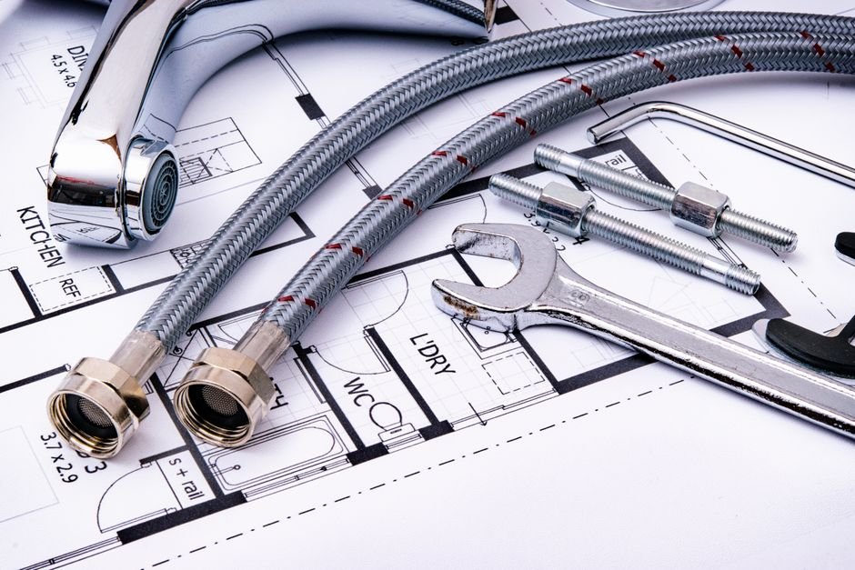 Plumbing wrench and pipe fittings laid over a house blueprint, the kind of job a Helensburgh plumber quotes for