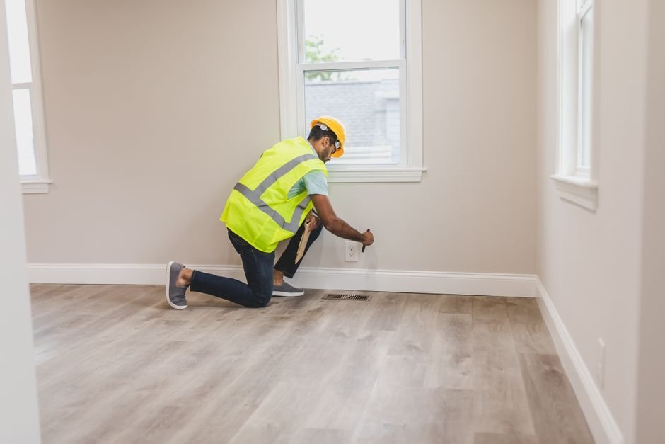 Tradesperson in a high-visibility vest checking an electrical fitting during a home safety inspection