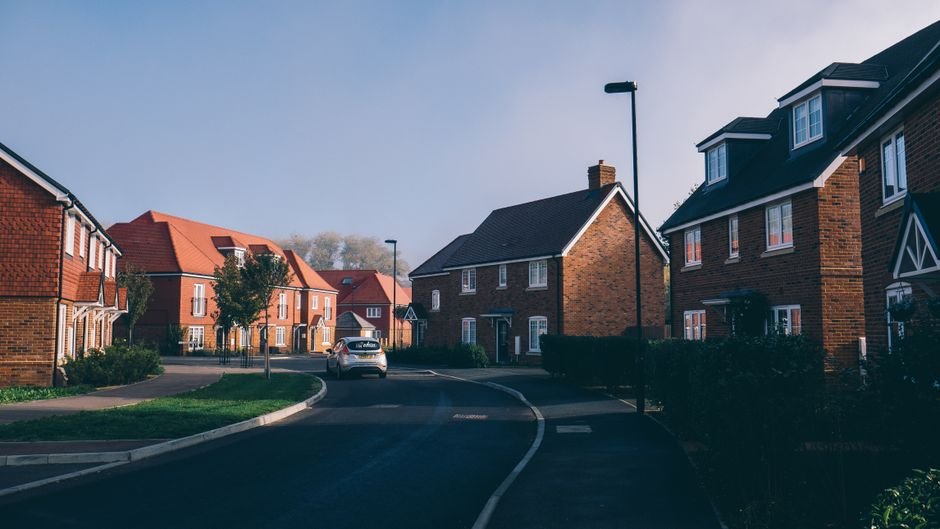 Quiet suburban street lined with brick detached and semi-detached houses, similar to the housing found across Milngavie