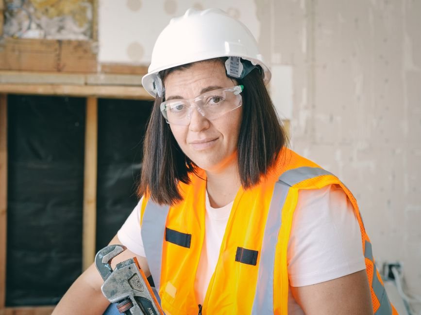 Plumber in safety gear holding a wrench, ready to start a boiler or pipework repair job