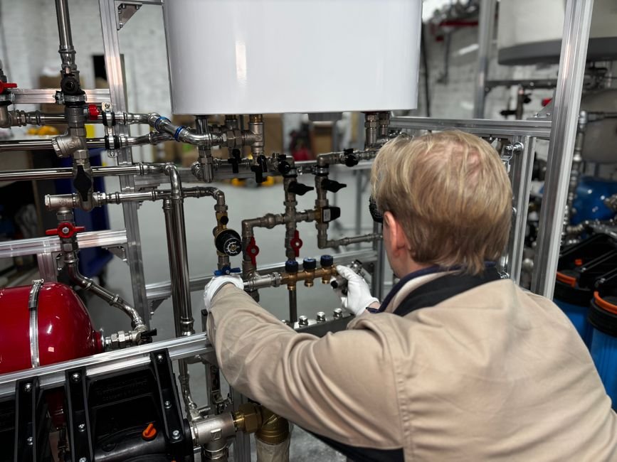 Heating engineer adjusting pipework, illustrative of the plumbing and gas work involved in a boiler repair call-out