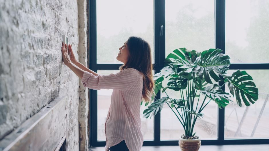 Hand adjusting a wall-mounted thermostat, the kind of heating control check worth doing before calling out a boiler engineer