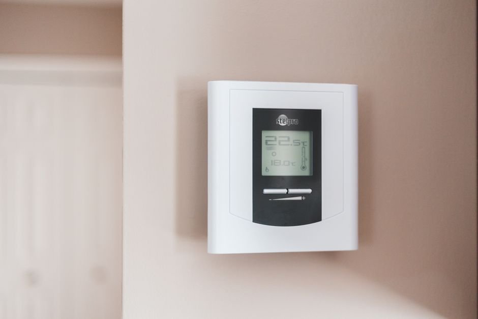 Modern digital heating thermostat mounted on a wall in a Troon home